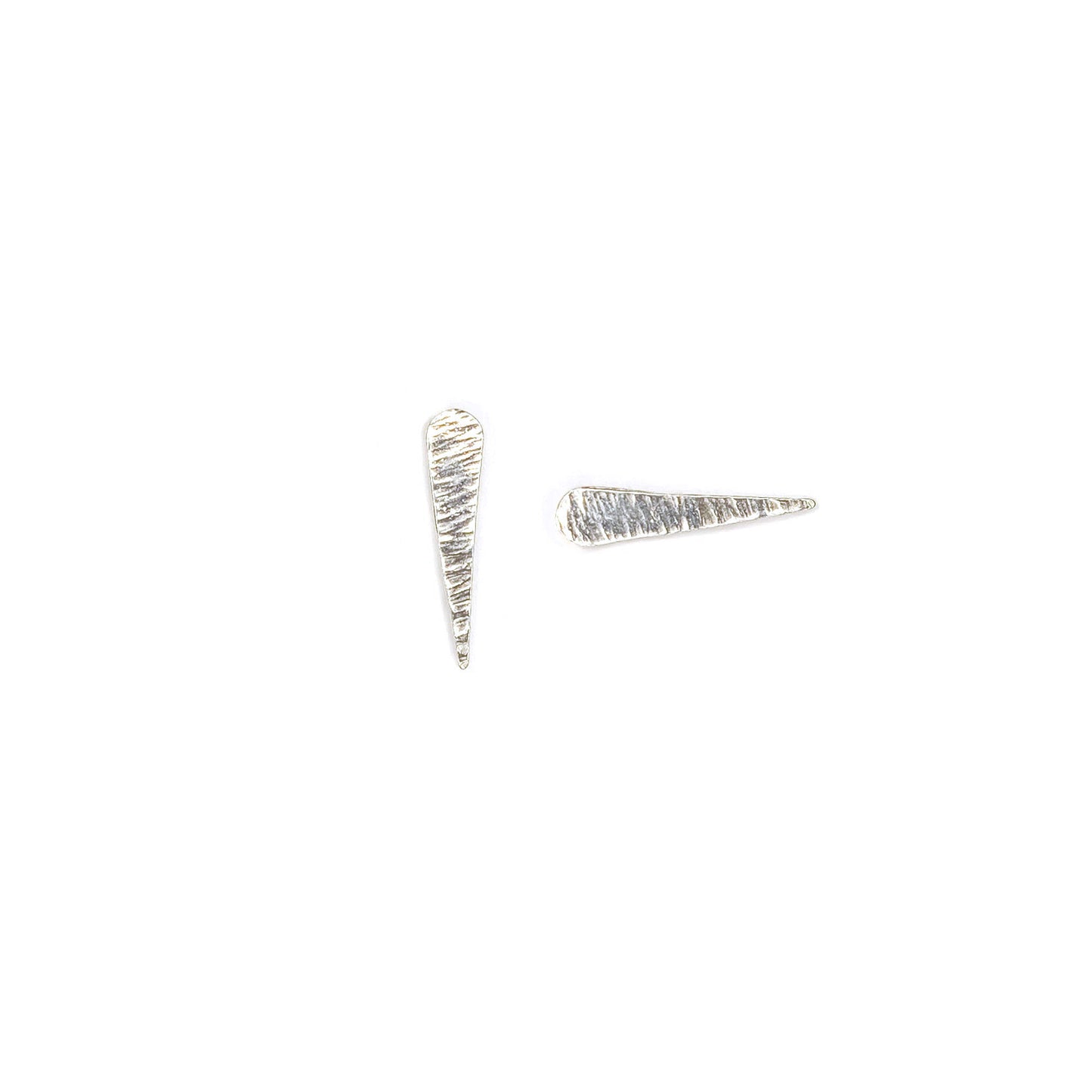 Silver, textured studs shaped like comets and their tails on a white background. One earring is positioned vertially, one horizontally.