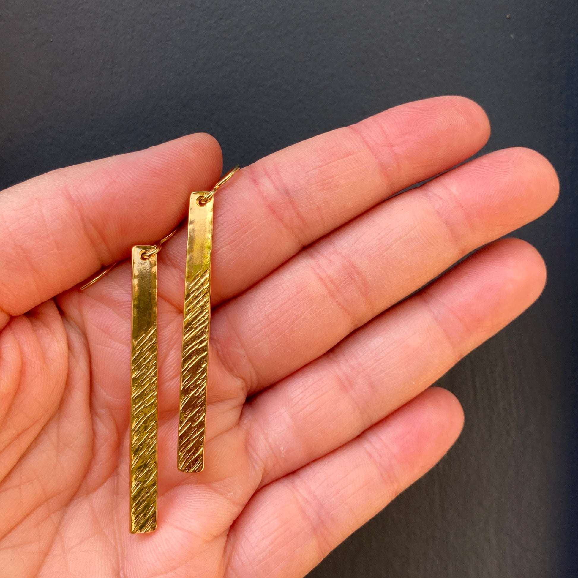Hand with front view of gold barred earrings