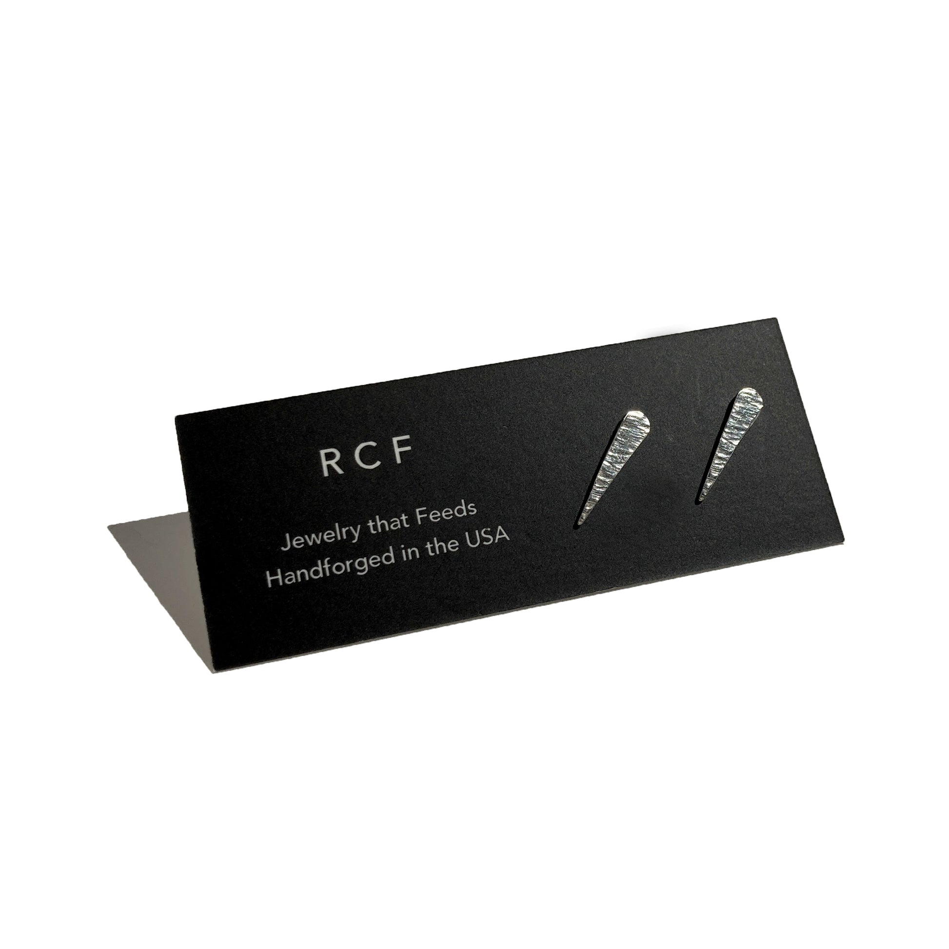 Silver, textured studs shaped like comets and their tails on an RCF earring card with a white background