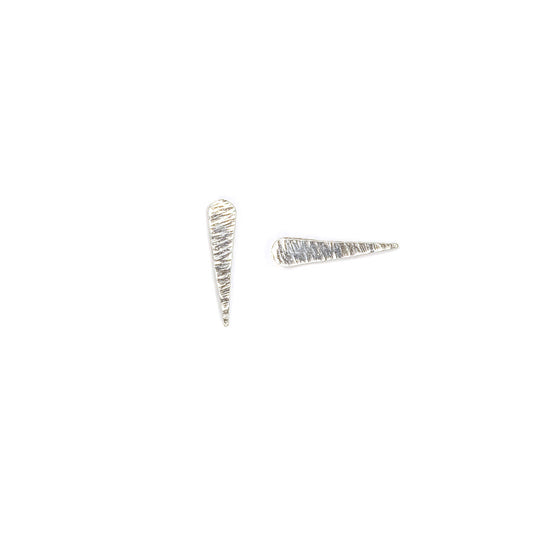 Silver, textured studs shaped like comets and their tails on a white background. One  earring is positioned vertially, one horizontally.