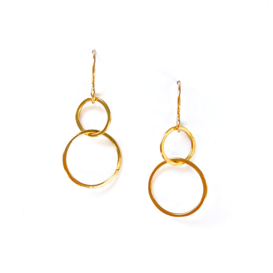 One small circle linked with a larger circle dangle earrings in gold on a white background