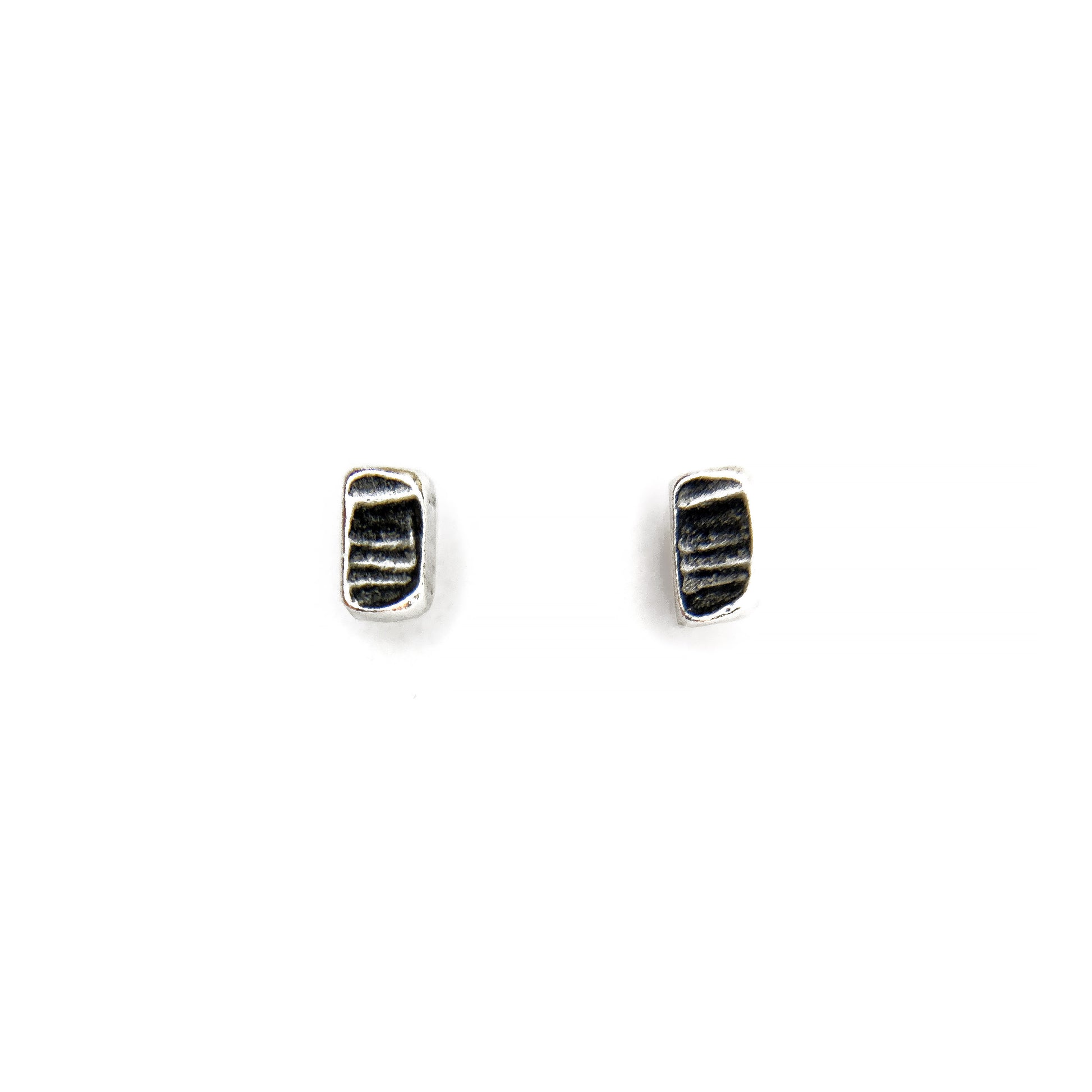 Two tiny silver textured stud earrings on a white background
