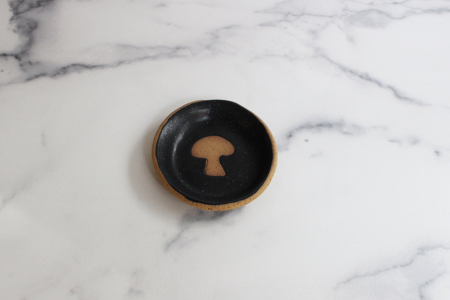 Black ceramic dish with a mushroom design